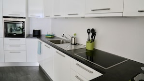 Eine moderne Küche mit weißen Schränken, einer schwarzen Arbeitsplatte und einem eingebauten Backofen.