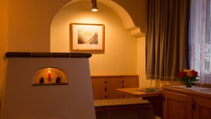 A cozy room with a fireplace, a bench, and a window with curtains. - Krepperhütte (Volders)