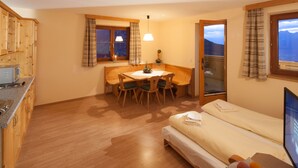 A compact room with a kitchenette, a dining area, and a bed. - Krepperhütte (Volders)