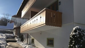 Un bâtiment à deux étages doté d’un balcon en bois et dont le sol est recouvert de neige.