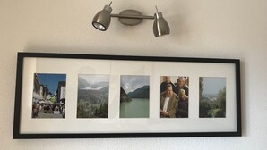 Un montage de photos encadrées est accroché au mur, et un luminaire est fixé au plafond juste au-dessus.