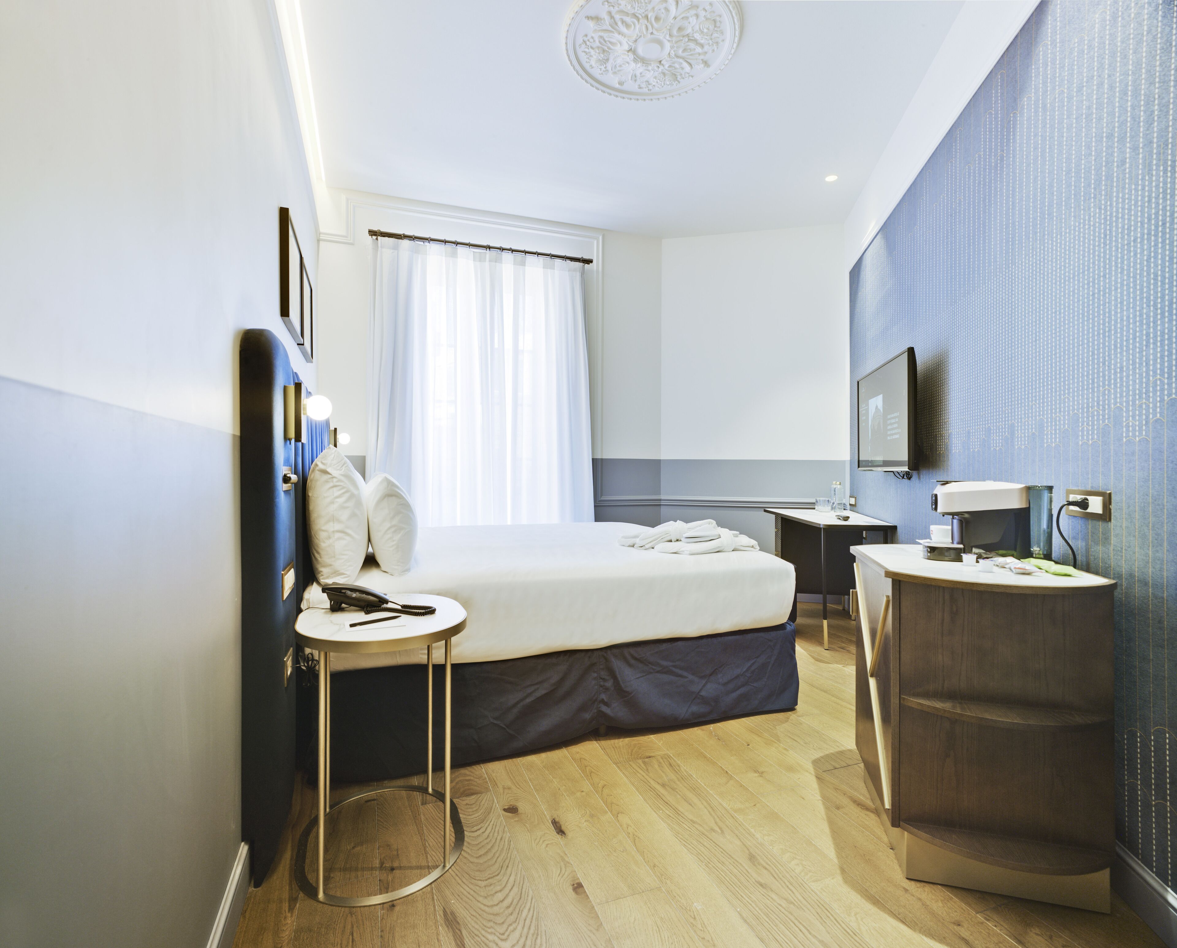 Une chambre d’hôtel moderne équipée d’un lit, d’une table de chevet et d’un bureau avec une chaise.