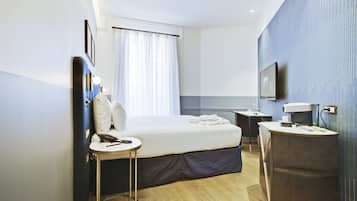 Une chambre d’hôtel moderne équipée d’un lit, d’une table de chevet et d’un bureau avec une chaise.