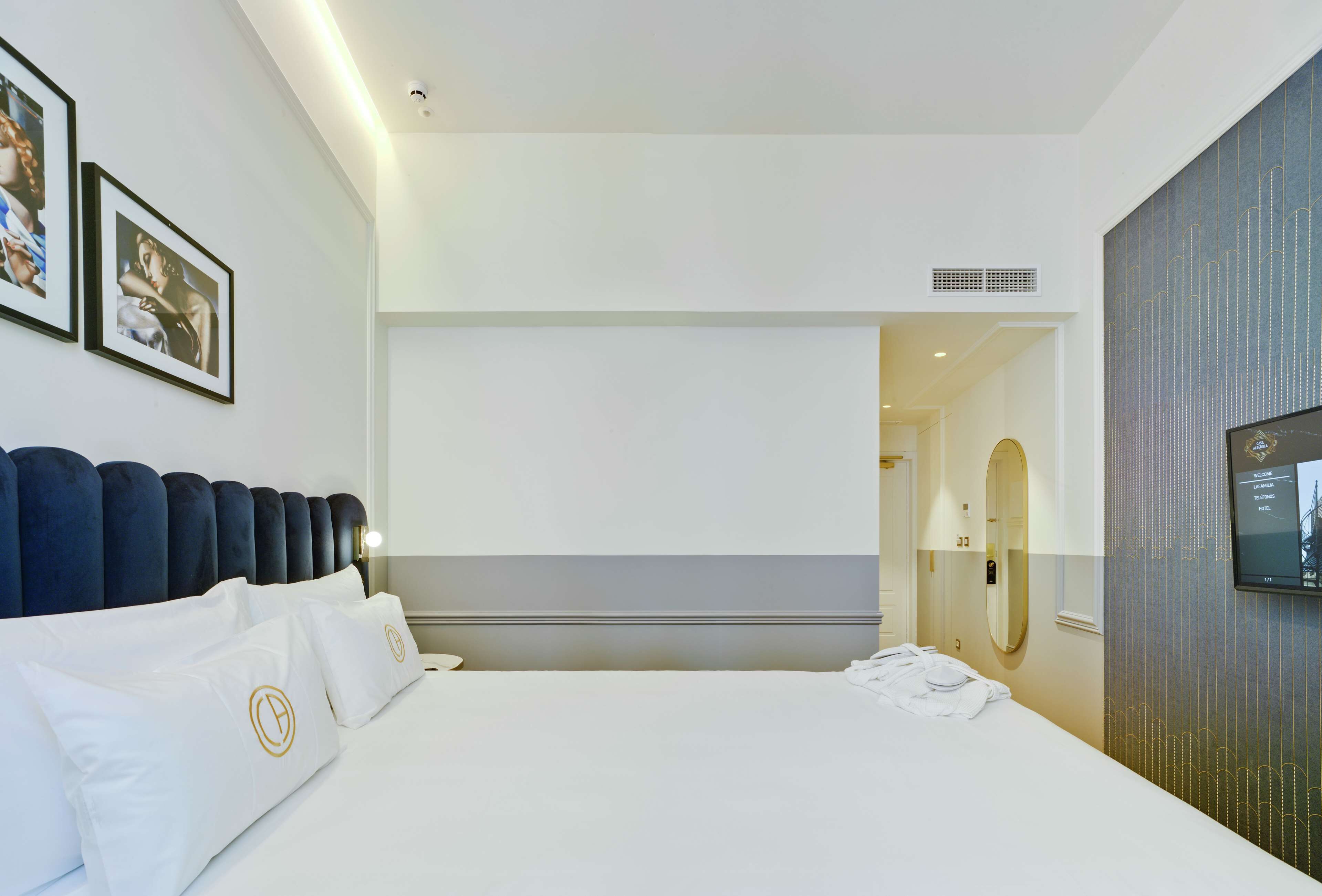 A modern hotel room with a large bed, a TV, and a bathroom visible through an open door.