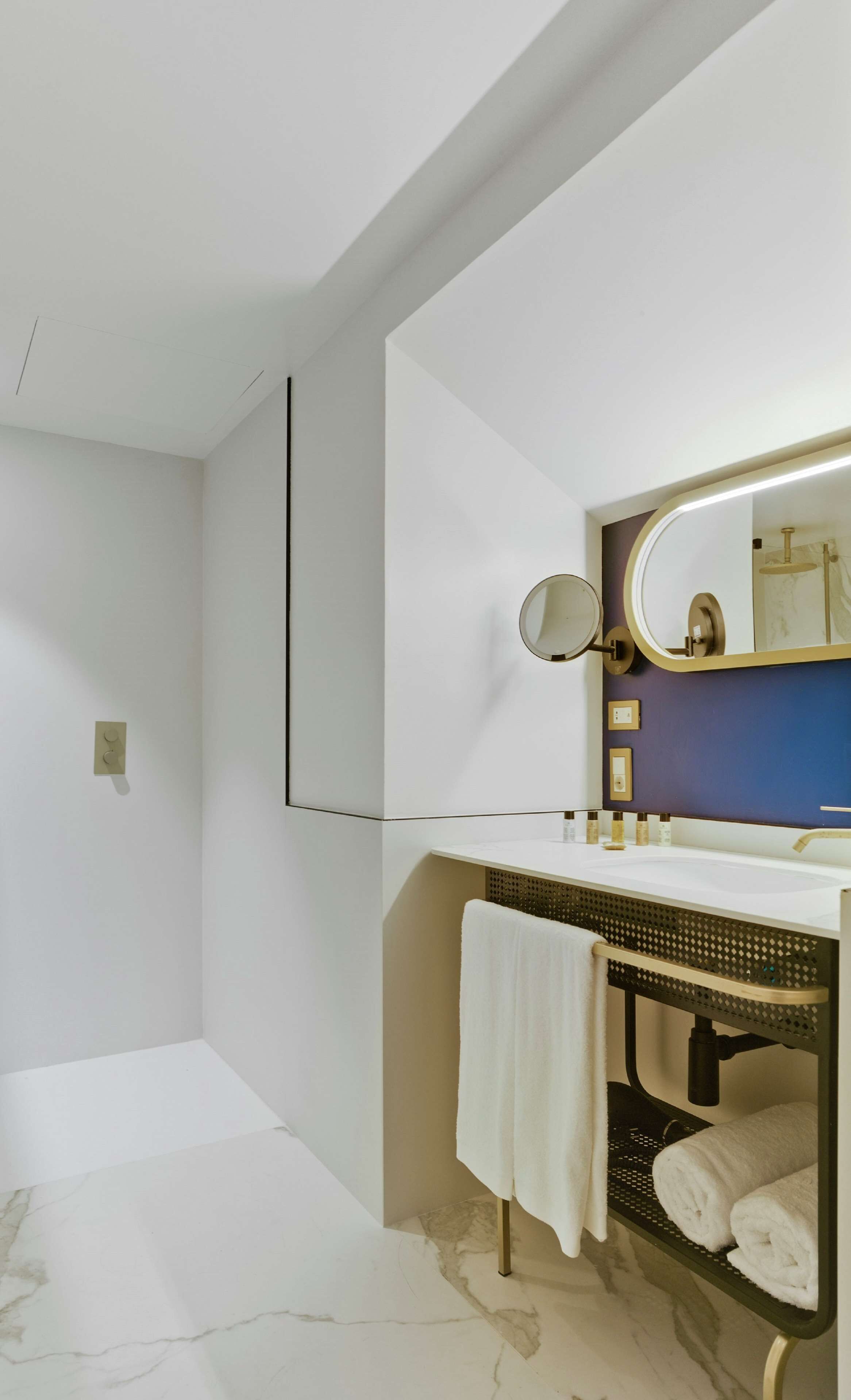 Un baño moderno con un tocador blanco, un espejo grande y un perchero para toallas.