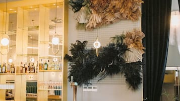 Un espace bar doté d’un comptoir en bois, de tabourets de bar et d’un mur décoratif orné de feuillages.