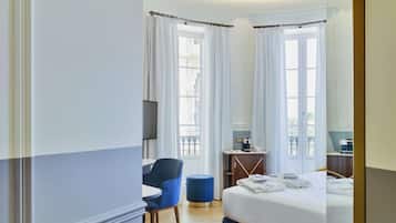 A hotel room with a bed, a desk, a chair, and a TV.