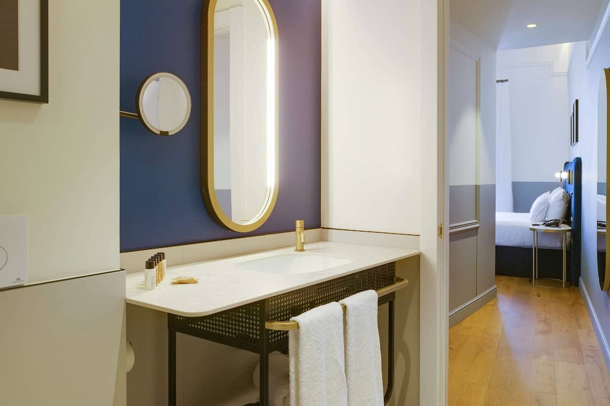 A modern bathroom with a large mirror, a white sink, and a towel rack.