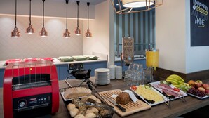 A breakfast buffet with various food items, a coffee machine, and a juice dispenser.