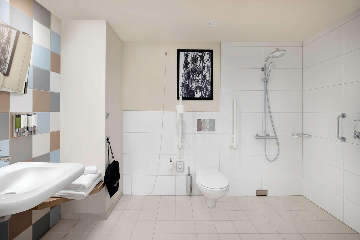Un baño moderno con lavamanos, inodoro y ducha.