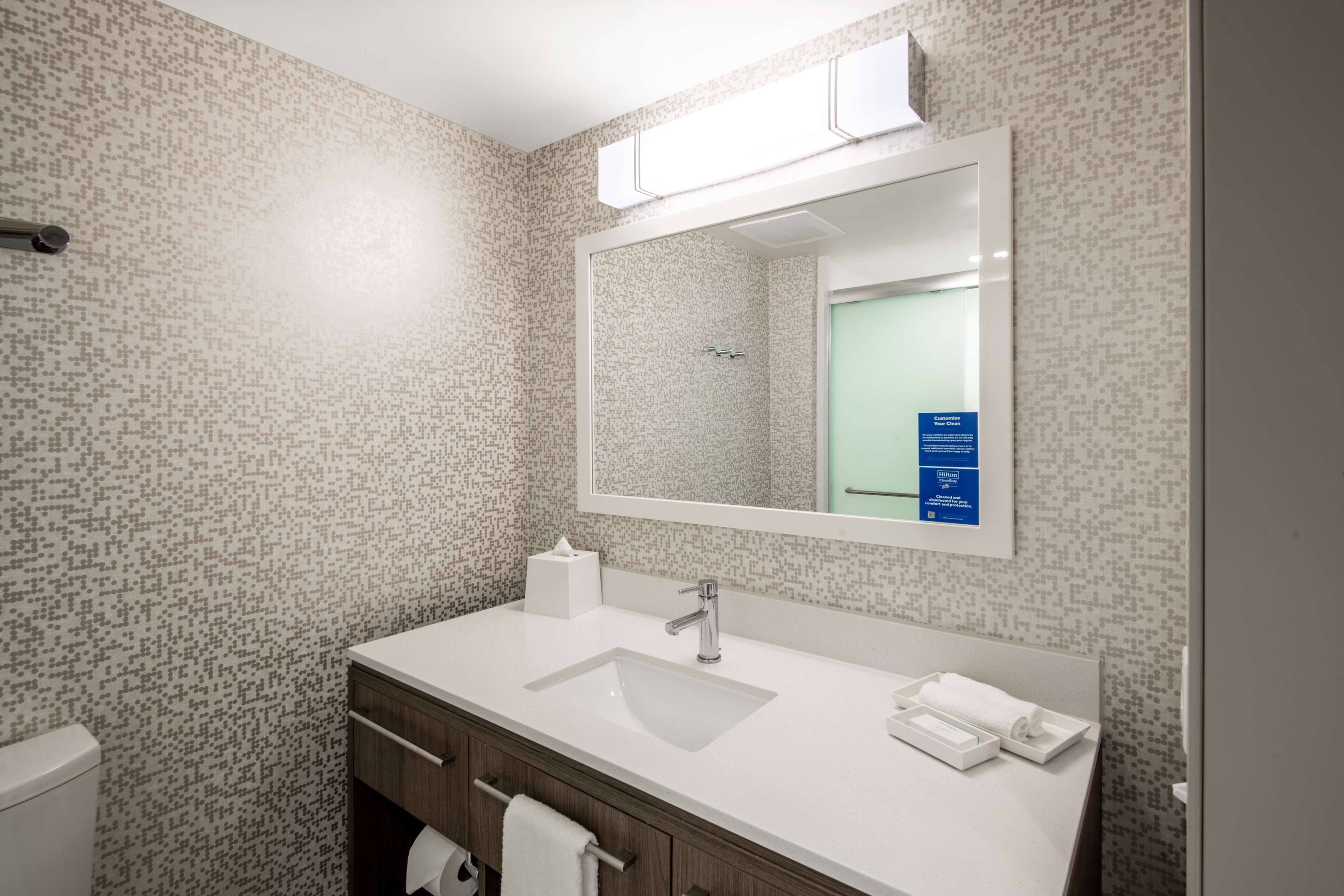 A bathroom with a white sink, mirror, and tiled walls.