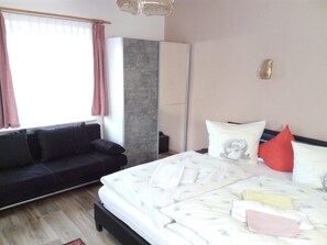 Ein Schlafzimmer mit einem Bett, einer Couch, einem Kleiderschrank und einem Fenster mit Vorhängen.