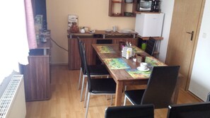 Eine kleine Küche mit Holztisch, Stühlen und einem Kühlschrank.