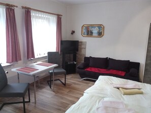 Ein Zimmer mit einem Bett, einer Couch, einem Fernseher, einem Kamin und einem Essbereich mit Tisch und Stühlen.