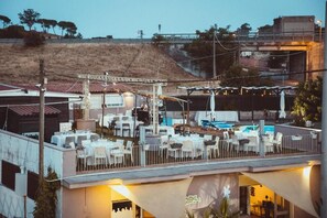 A rooftop restaurant with outdoor seating, a pool, and a view of a hillside. - Cosi Priziusi B&B Relais (Vizzini)