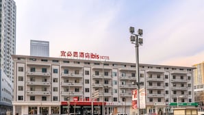 Ein mehrstöckiges Hotel mit Balkonen, einer markanten Schilder und einem wolkenlosen Himmel.