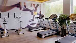 Un gimnasio con cintas de correr, elípticas y un amplio muro de espejos.