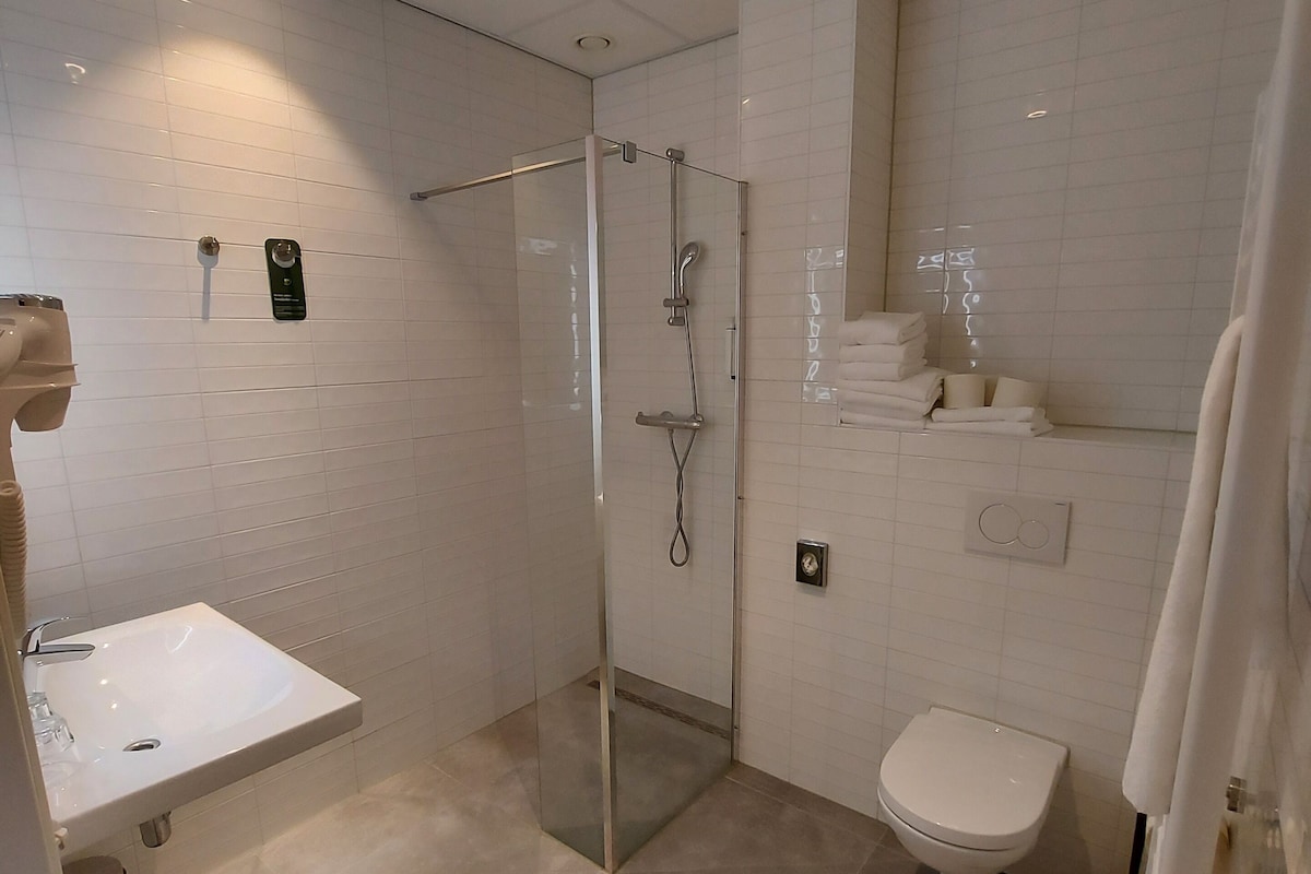 A modern bathroom with a glass-enclosed shower, a white sink, and a toilet.