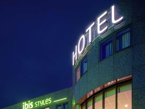 A hotel building with illuminated signage reading "HOTEL" and "ibis styles".