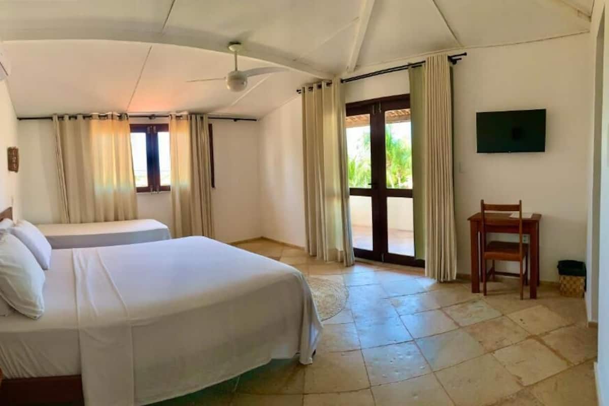 Ein Hotelzimmer mit zwei Betten, einem Deckenventilator, einem Fernseher und Blick ins Freie.
