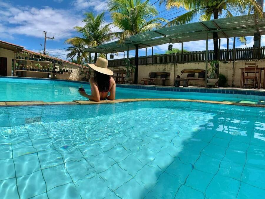 Una piscina con agua azul cristalina, rodeada de palmeras y una zona de estar cubierta.