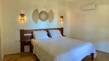 A neatly made bed with white linens, a wooden headboard, and two wall-mounted sconces.