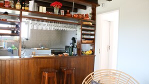 Un coin bar en bois avec des tabourets, une chaise en osier et des appareils de cuisine.