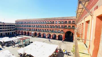 Une cour intérieure bordée d’un immeuble à plusieurs étages, doté d’arcades et de balcons.