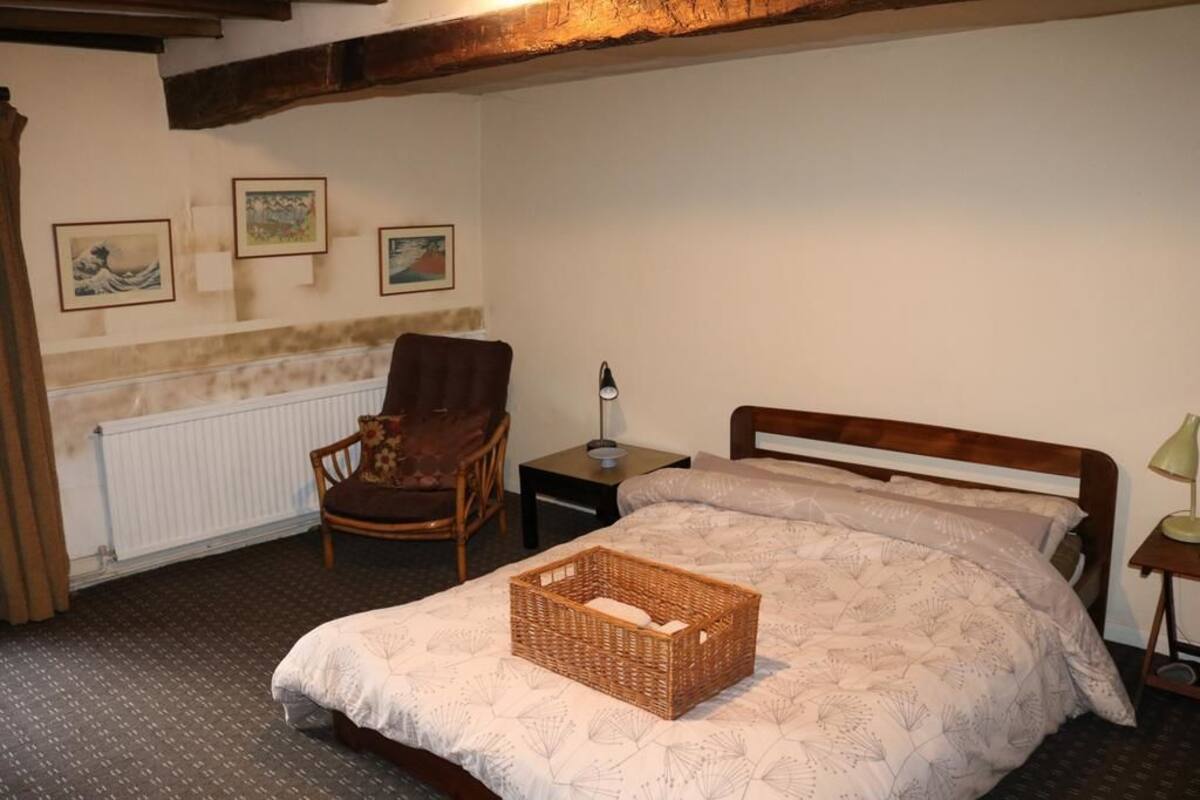 A bedroom with a bed, a chair, a nightstand, and a radiator.