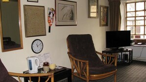 A living room with a brown armchair, a television, and framed pictures on the wall. - sweet heART Tea Rooms Accommodation (Harrogate)