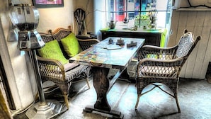 A room with wicker furniture, a table with papers, and a window with a view of the street. - sweet heART Tea Rooms Accommodation (Harrogate)