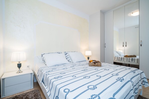 A bedroom with a bed, nightstand, lamp, and wardrobe.