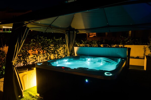 A hot tub under a canopy with a view of a building in the background. - Villa Luciana Residence (Zupa dubrovacka)