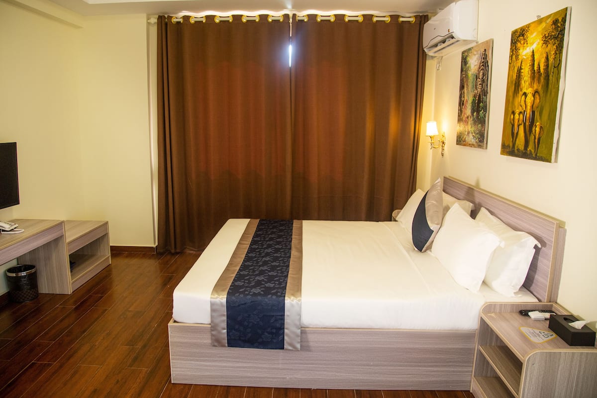 Une chambre d’hôtel avec un lit, une table de chevet, une lampe et une œuvre d’art accrochée au mur.