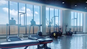 A gym with various exercise equipment, large windows, and a view of the sky. - City Comfort Airport Hotel Phnom Penh (Phnom Penh)