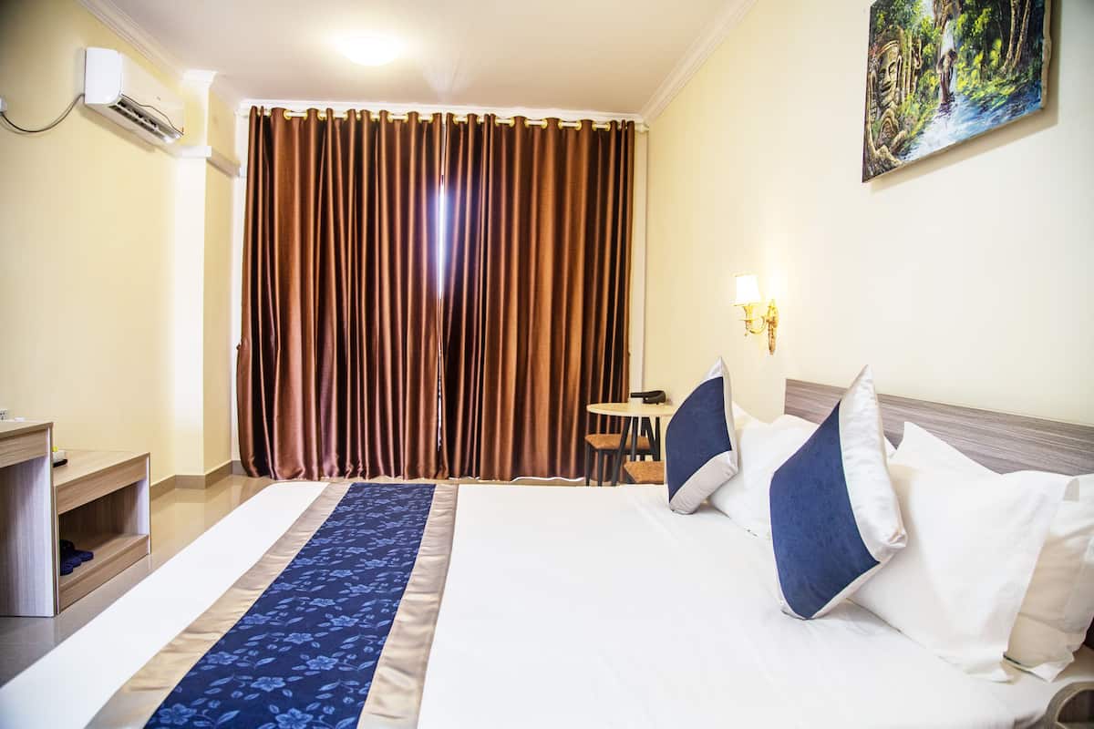 Une chambre d’hôtel avec un lit, un bureau, une chaise et un tableau au mur.