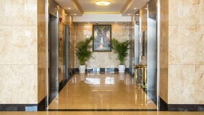 A polished marble lobby with a central painting, potted plants, and a modern elevator. - City Comfort Airport Hotel Phnom Penh (Phnom Penh)