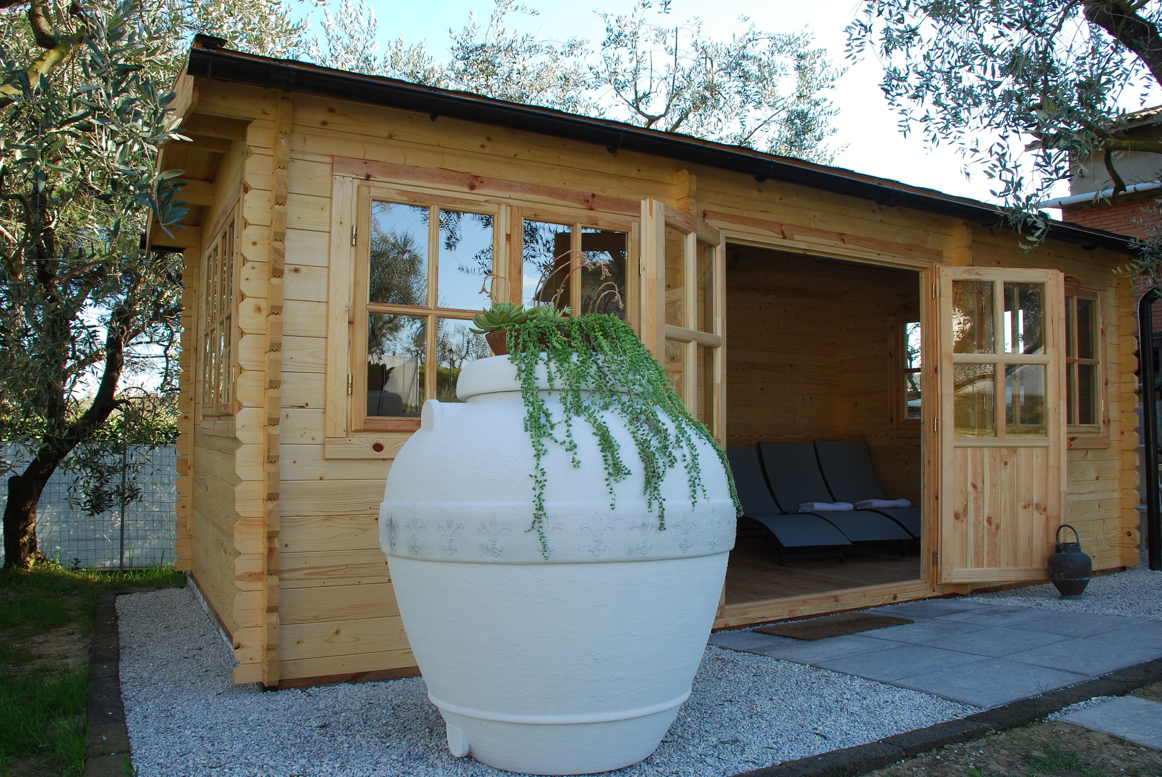Una cabaña de madera con una maceta blanca grande al frente.