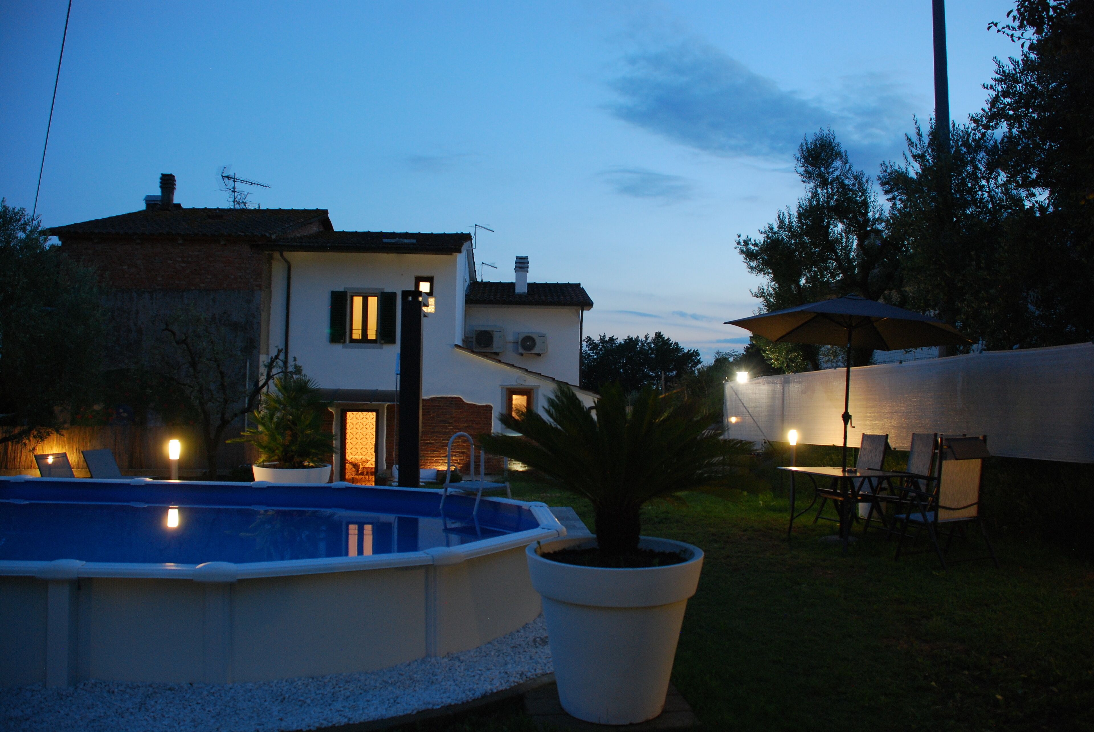 A residential property with a swimming pool, outdoor seating, and a well-lit patio area.