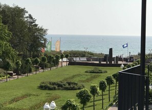 Eine angelegte Grünfläche mit Meerblick, mit Rasen, Bäumen und einer Sitzgelegenheit mit einer Flagge.