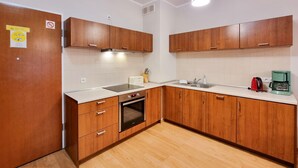 A modern kitchen with wooden cabinets, a built-in oven, a sink, and a coffee maker. - Platane (CH10) - CH10 (Swinoujscie)