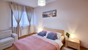 A bedroom with a bed, a chair, a nightstand, a lamp, and a painting on the wall. - Platane (CH10) - CH10 (Swinoujscie)