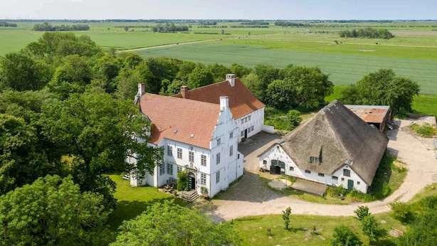 A large white building with a red roof, surrounded by lush greenery and fields. - Apartment 4 Anna Owena (ID 386) (Oldenswort)