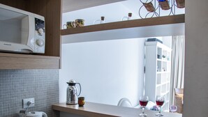 Una cocina con microondas, cafetera y copas de vino sobre la encimera.