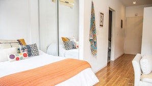 Un dormitorio con una cama grande, un sofá blanco y suelo de madera.