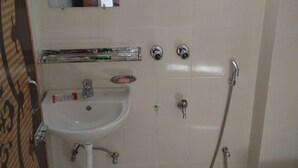 Une salle de bain équipée d’un lavabo, d’un miroir, d’une douche et de toilettes.