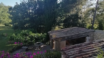 A garden with a stone building, surrounded by trees and vibrant flowers.