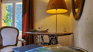 A room with a table, a chair, a lamp, a bowl, and a window with curtains. - Le Mas des Escans (Le Beausset)