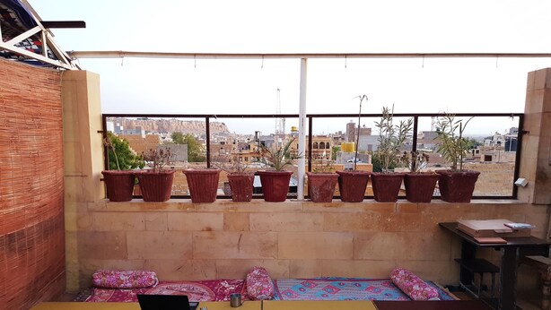 Une terrasse sur le toit, aménagée avec un espace salon, des plantes en pot et un ordinateur portable posé sur une table.