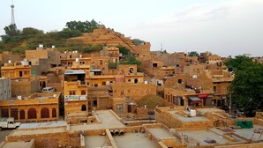 Une zone urbaine densément peuplée, caractérisée par une architecture traditionnelle, et comprenant une colline imposante surmontée d’une petite construction.